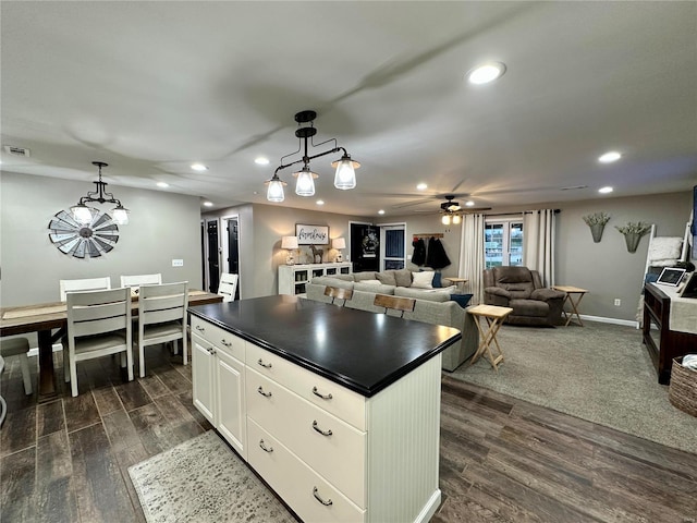 kitchen with ceiling fan, a center island, dark hardwood / wood-style flooring, decorative light fixtures, and white cabinets