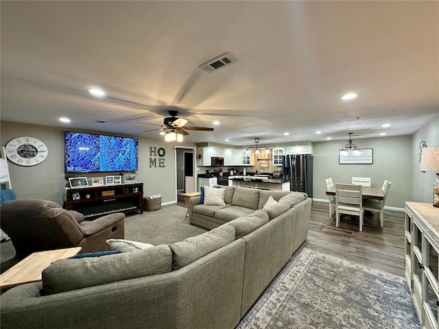 living room featuring ceiling fan with notable chandelier and wood-type flooring