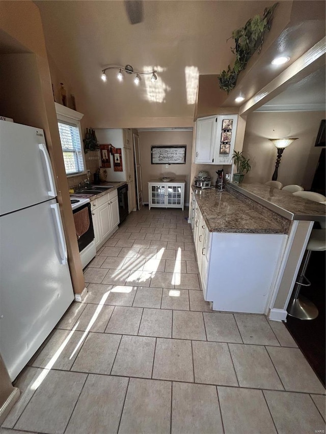 kitchen featuring white cabinetry, sink, crown molding, dark stone counters, and white appliances