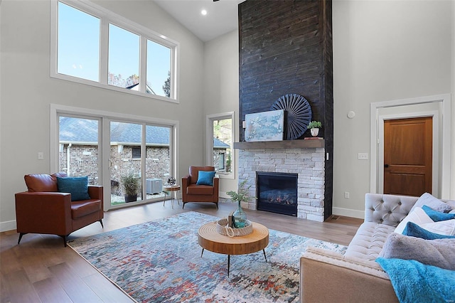 living room featuring a fireplace, light wood-type flooring, and a towering ceiling