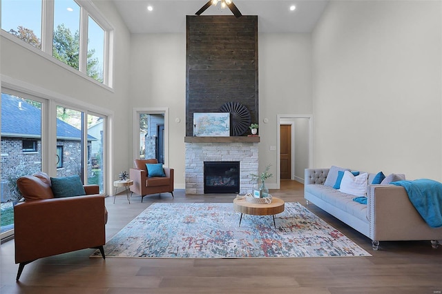 living room featuring a wealth of natural light, a fireplace, a high ceiling, and hardwood / wood-style flooring