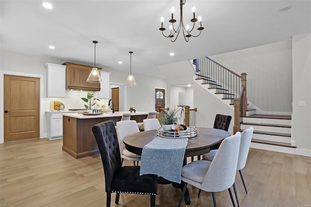 dining room featuring a chandelier, sink, and light hardwood / wood-style flooring