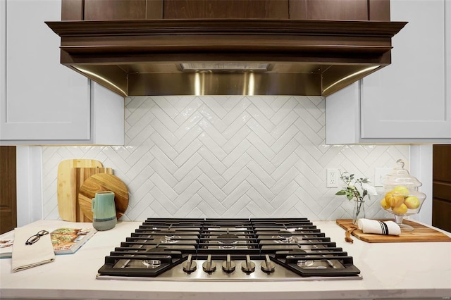 kitchen featuring decorative backsplash, white cabinetry, custom range hood, and stainless steel gas cooktop