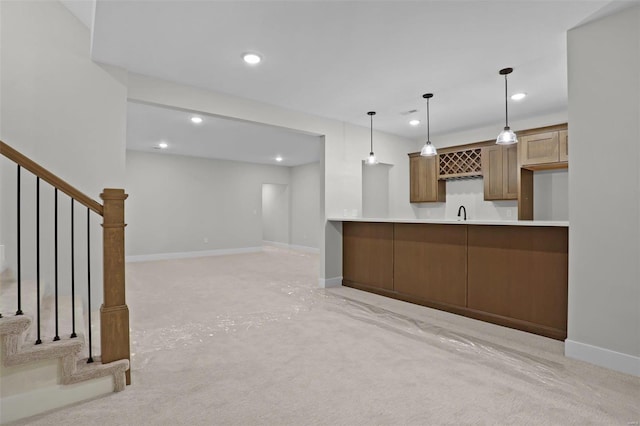 kitchen featuring kitchen peninsula, light colored carpet, and decorative light fixtures