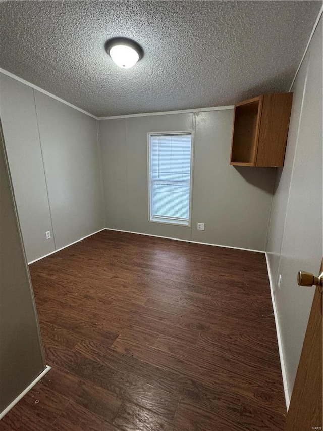 spare room featuring dark hardwood / wood-style flooring, ornamental molding, and a textured ceiling