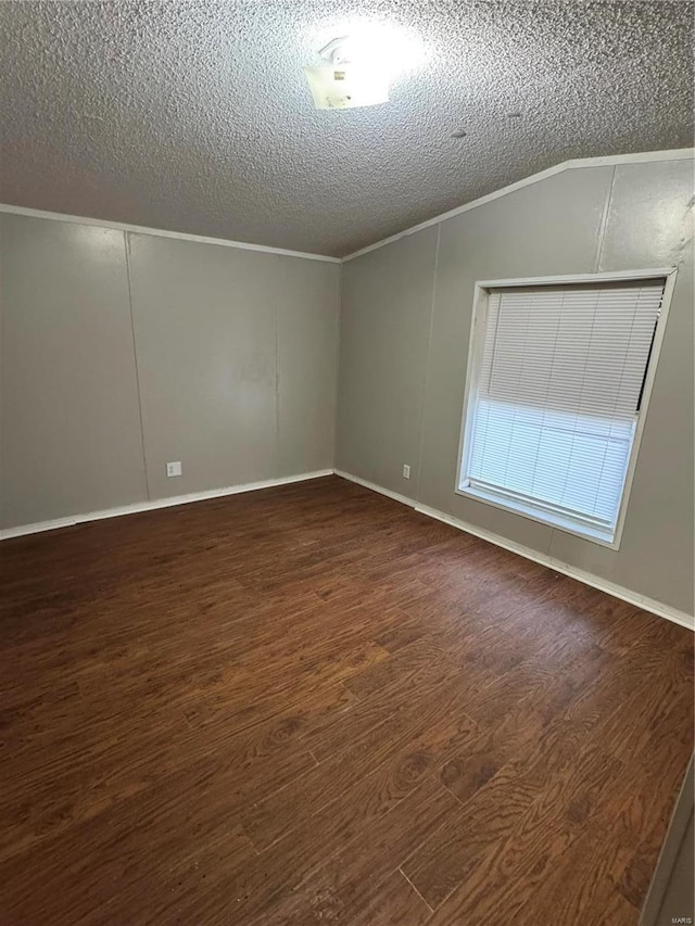 empty room featuring a textured ceiling, crown molding, vaulted ceiling, and dark hardwood / wood-style floors