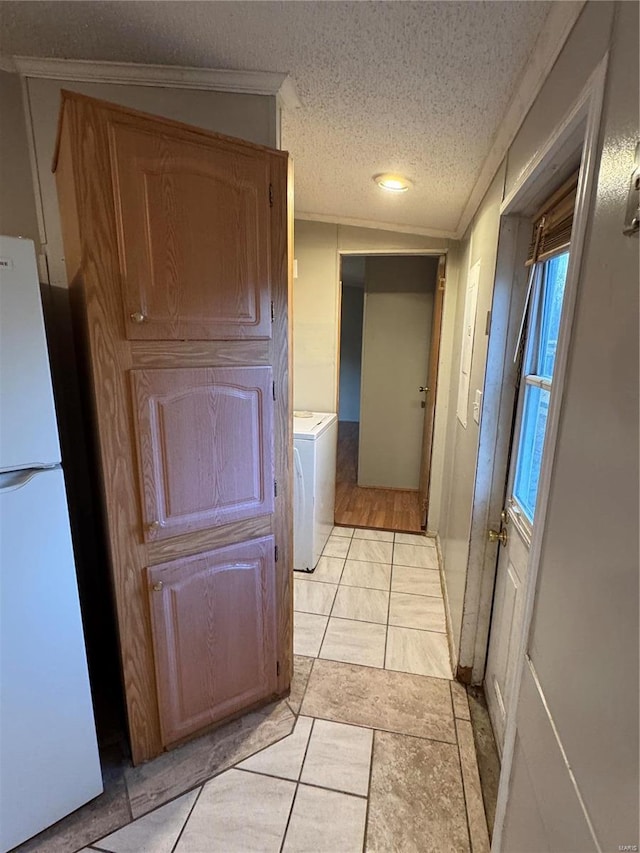 hall with washer / clothes dryer, light tile patterned flooring, and a textured ceiling