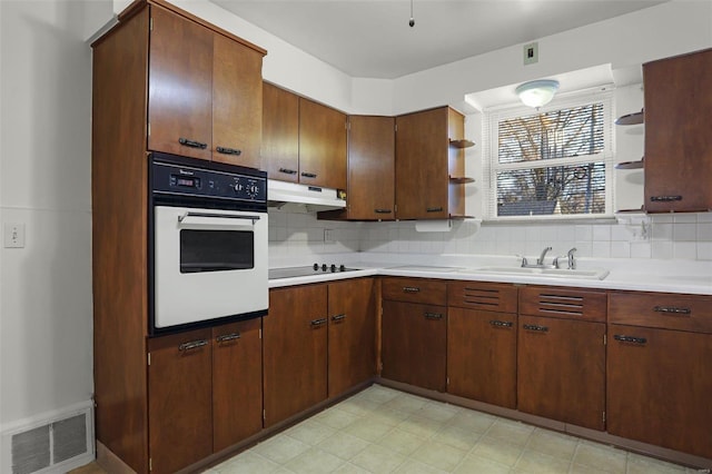 kitchen featuring tasteful backsplash, sink, oven, and black electric stovetop