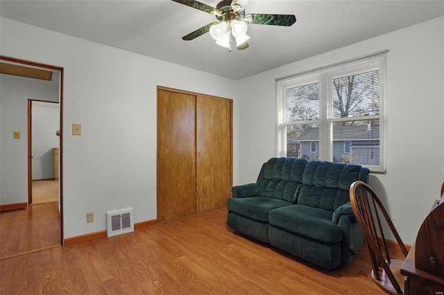 living area with ceiling fan and light hardwood / wood-style flooring