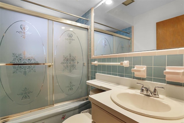 full bathroom featuring vanity, bath / shower combo with glass door, toilet, tile walls, and tasteful backsplash