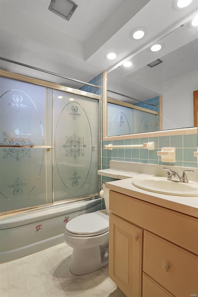 full bathroom featuring combined bath / shower with glass door, vanity, tile walls, tile patterned flooring, and toilet