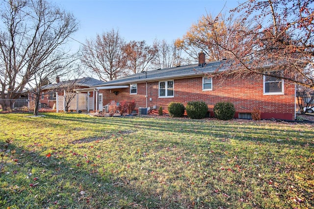 rear view of house with a yard and central AC