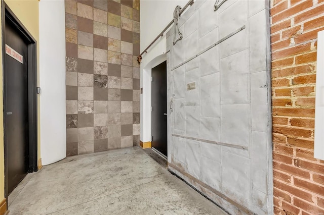 corridor featuring concrete flooring and brick wall