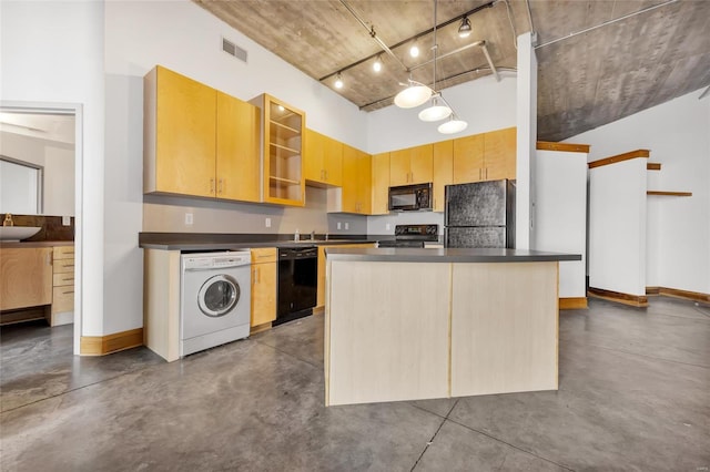 kitchen featuring sink, washer / clothes dryer, concrete flooring, a kitchen island, and black appliances