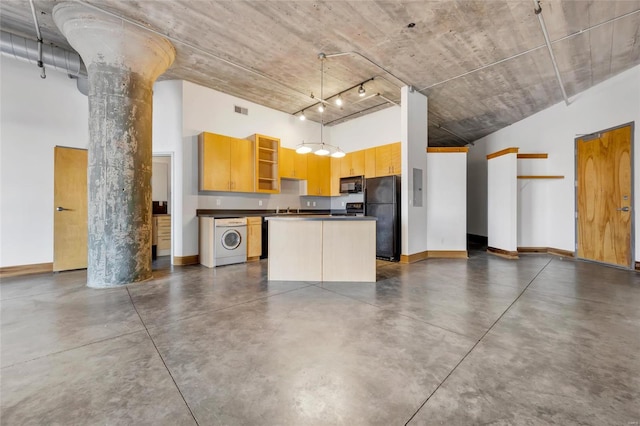 kitchen featuring ornate columns, a center island, washer / clothes dryer, decorative light fixtures, and black appliances