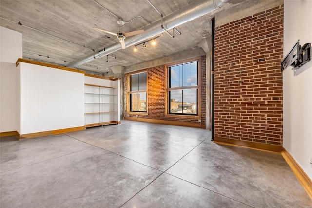 empty room featuring ceiling fan, concrete floors, and brick wall