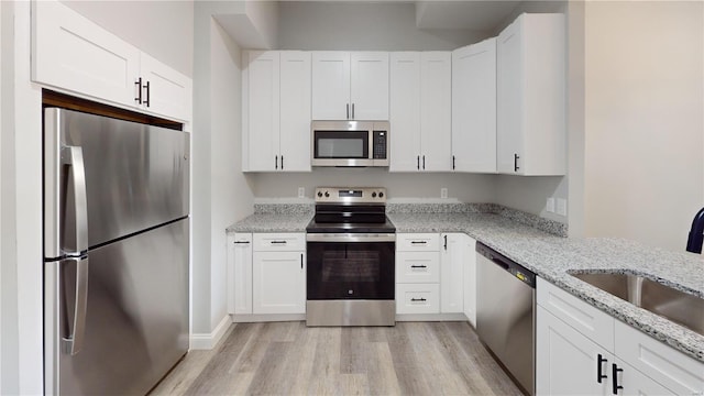 kitchen featuring light hardwood / wood-style flooring, white cabinets, stainless steel appliances, and sink