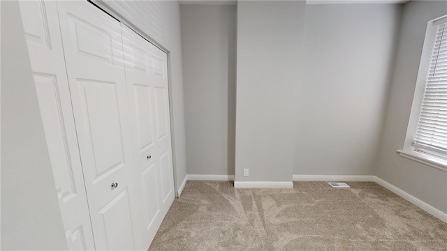 unfurnished bedroom featuring light carpet and a closet