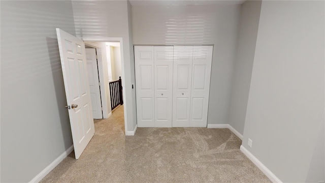 unfurnished bedroom with light colored carpet and a closet