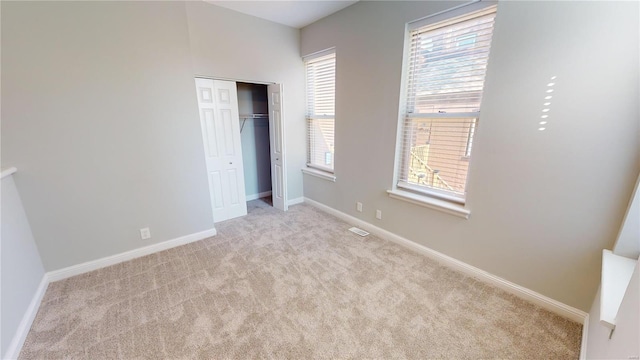 unfurnished bedroom featuring a closet, light carpet, and multiple windows