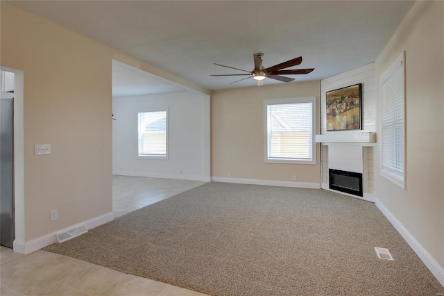 unfurnished living room with plenty of natural light, ceiling fan, and light colored carpet