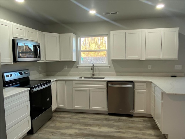 kitchen featuring white cabinetry, sink, stainless steel appliances, and light hardwood / wood-style floors