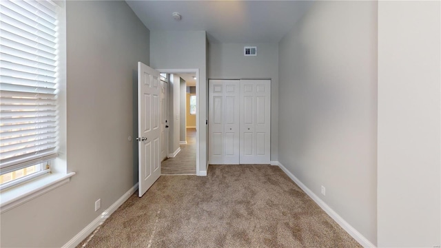 unfurnished bedroom with a closet and light colored carpet