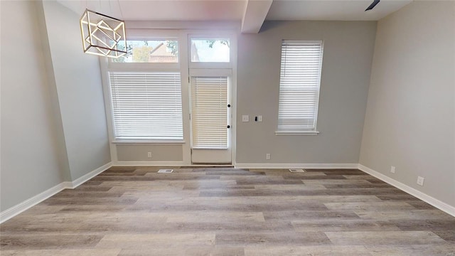 empty room with beam ceiling and light hardwood / wood-style flooring