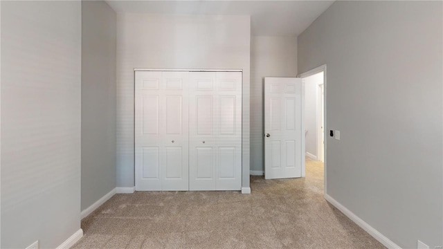 unfurnished bedroom with light carpet and a closet