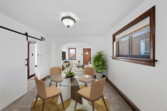 dining area featuring a barn door and light colored carpet