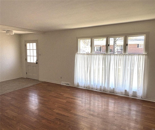 spare room featuring dark wood-type flooring and a healthy amount of sunlight