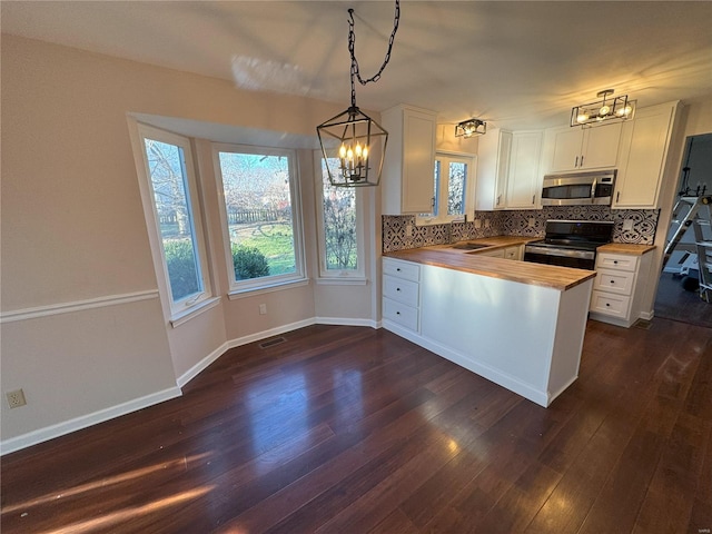 kitchen featuring butcher block counters, dark hardwood / wood-style flooring, black range, and decorative light fixtures