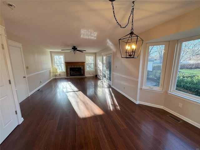 unfurnished living room featuring a fireplace, ceiling fan with notable chandelier, and dark hardwood / wood-style floors