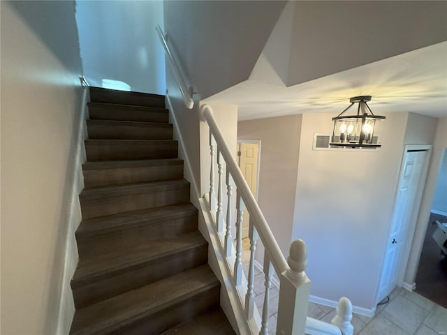 stairway featuring tile patterned floors and a notable chandelier