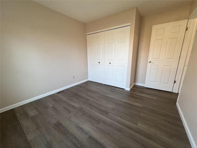 unfurnished bedroom featuring a closet and dark wood-type flooring