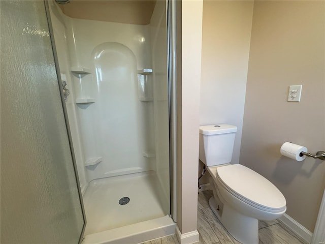 bathroom featuring a shower, hardwood / wood-style floors, and toilet