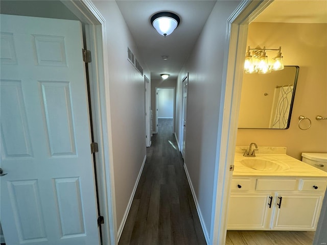 corridor with dark hardwood / wood-style flooring and sink