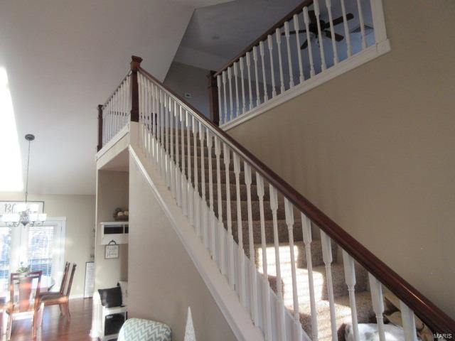 stairs featuring wood-type flooring, a towering ceiling, and a notable chandelier