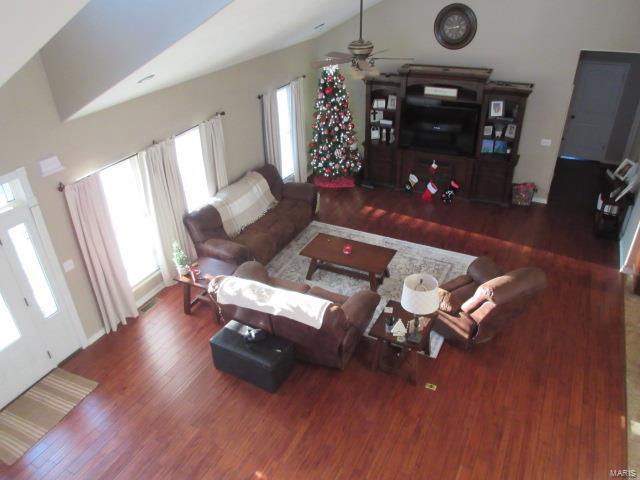 living room featuring dark hardwood / wood-style floors, vaulted ceiling, and ceiling fan