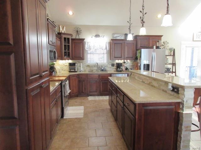 kitchen featuring decorative backsplash, stainless steel appliances, sink, pendant lighting, and a center island