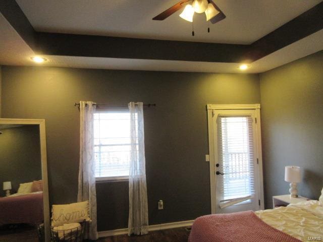 bedroom with hardwood / wood-style floors, a tray ceiling, and ceiling fan