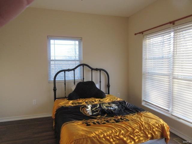 bedroom with multiple windows and dark wood-type flooring