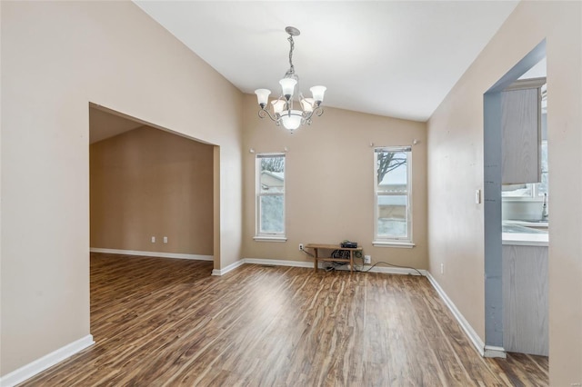 unfurnished dining area with dark wood-type flooring, vaulted ceiling, and a notable chandelier