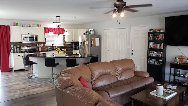 living room with hardwood / wood-style flooring, ceiling fan, and sink