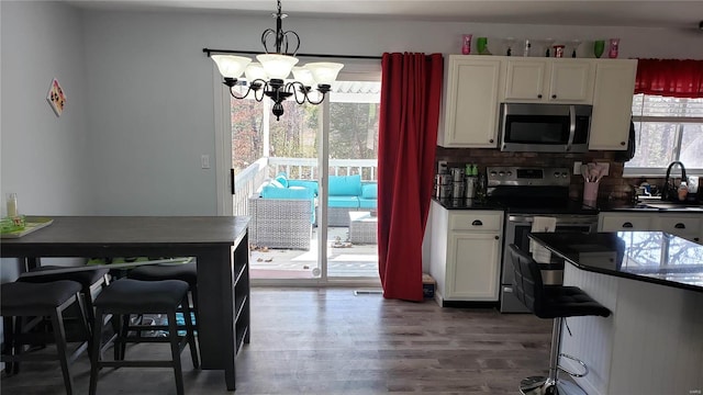 kitchen with tasteful backsplash, a chandelier, decorative light fixtures, white cabinets, and appliances with stainless steel finishes