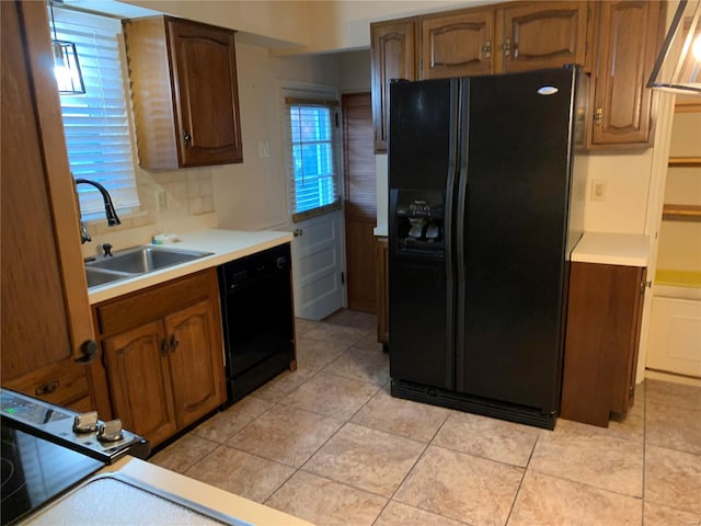 kitchen with backsplash, sink, light tile patterned flooring, and black appliances