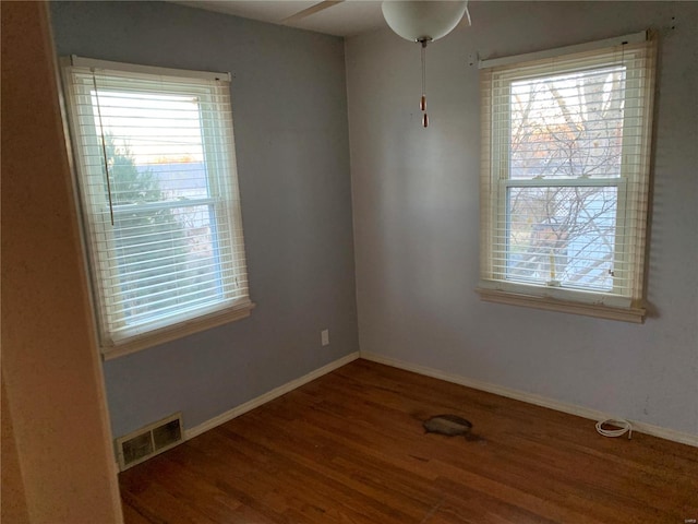 unfurnished room featuring plenty of natural light, dark hardwood / wood-style floors, and ceiling fan