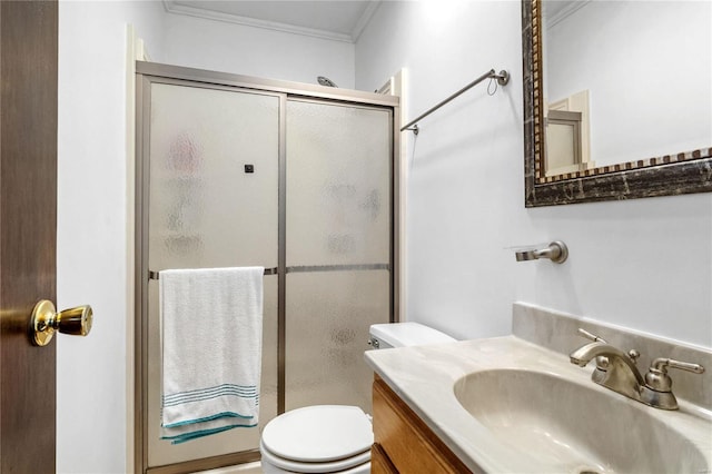 bathroom with vanity, toilet, a shower with shower door, and ornamental molding