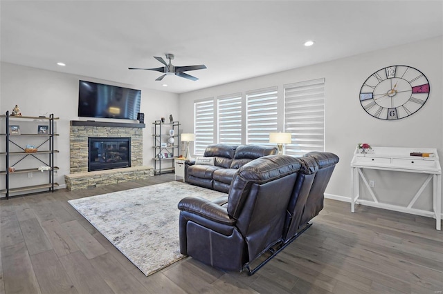 living room featuring a fireplace, ceiling fan, and dark wood-type flooring