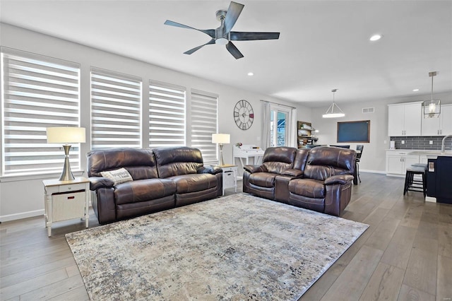 living room featuring ceiling fan, plenty of natural light, and light hardwood / wood-style floors